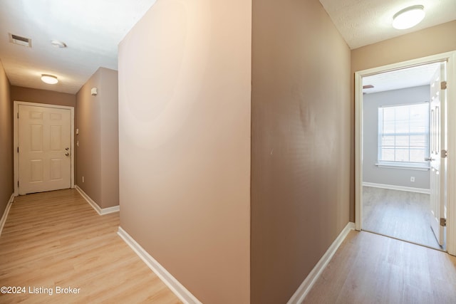 hallway featuring a textured ceiling and light wood-type flooring