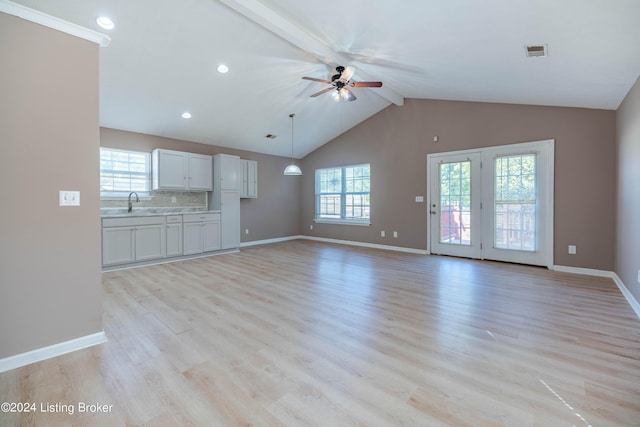 unfurnished living room with sink, light wood-type flooring, vaulted ceiling with beams, and ceiling fan