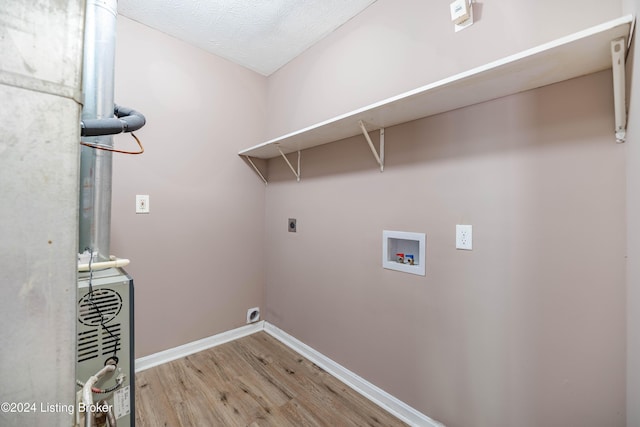 clothes washing area with hookup for a washing machine, electric dryer hookup, a textured ceiling, and hardwood / wood-style flooring