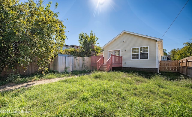 back of house with a deck and a lawn