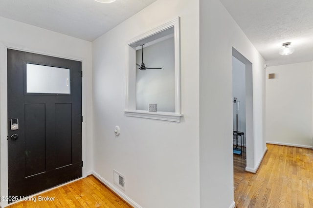 entrance foyer featuring ceiling fan, light hardwood / wood-style flooring, and a textured ceiling