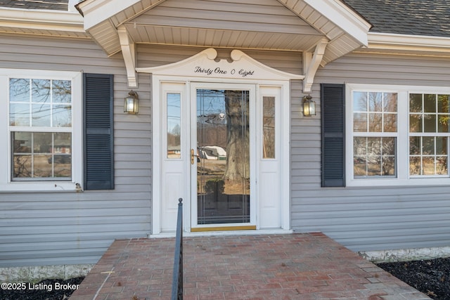 doorway to property with a shingled roof