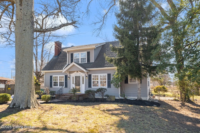 view of front of house with a front lawn, roof with shingles, a chimney, and fence