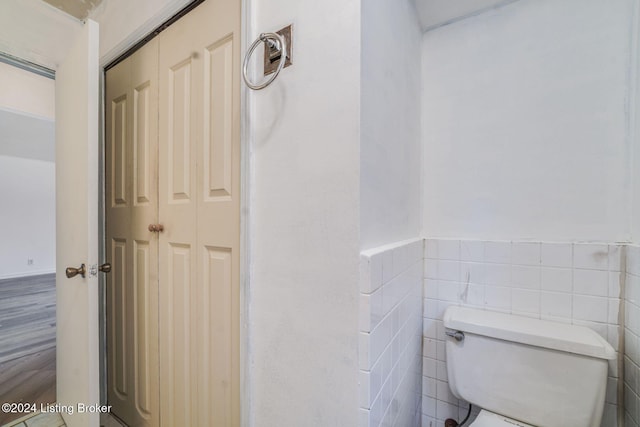 bathroom featuring tile walls and toilet