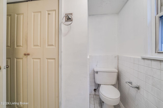 bathroom with tile walls, tile patterned floors, and toilet