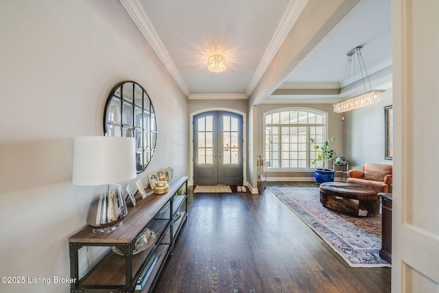 foyer entrance with dark hardwood / wood-style flooring, ornamental molding, and french doors