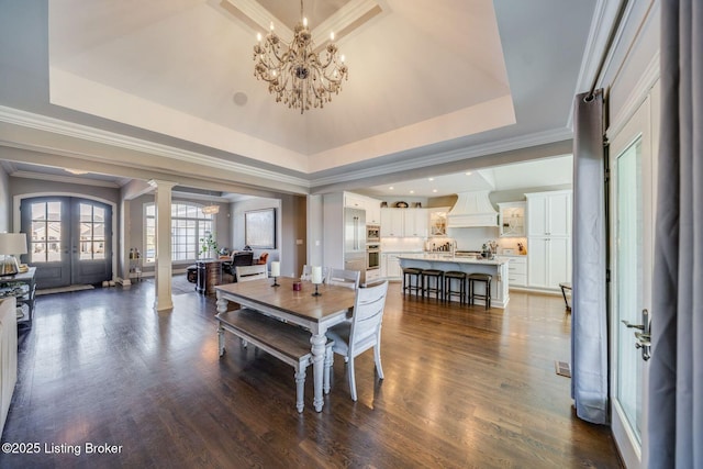 dining space with ornamental molding, ornate columns, a tray ceiling, and french doors