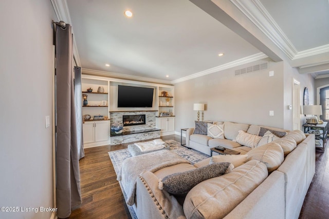 living room featuring built in shelves, dark wood-type flooring, a fireplace, and ornamental molding