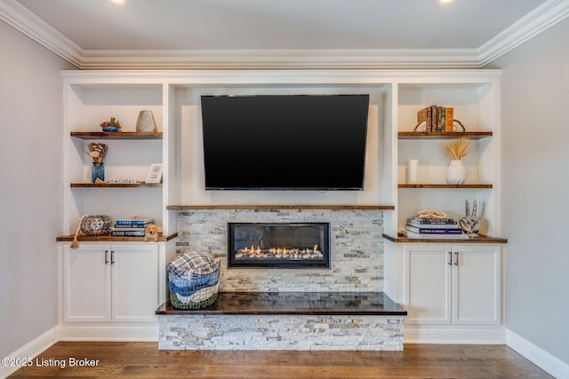 unfurnished living room featuring a stone fireplace, ornamental molding, and dark hardwood / wood-style floors