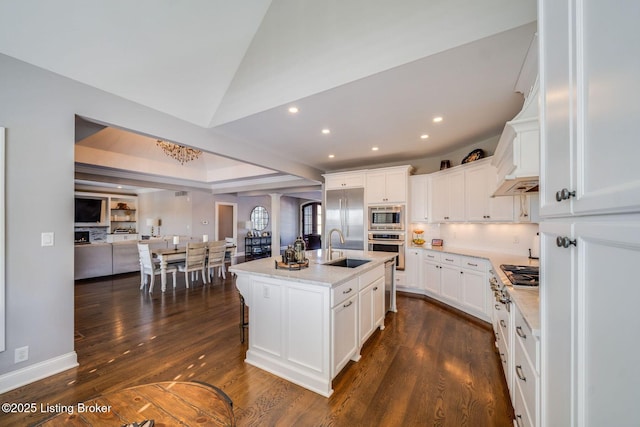 kitchen with sink, white cabinetry, light stone countertops, and an island with sink