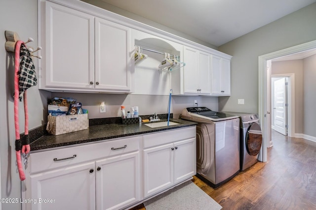 clothes washing area with light wood-type flooring, separate washer and dryer, cabinets, and sink