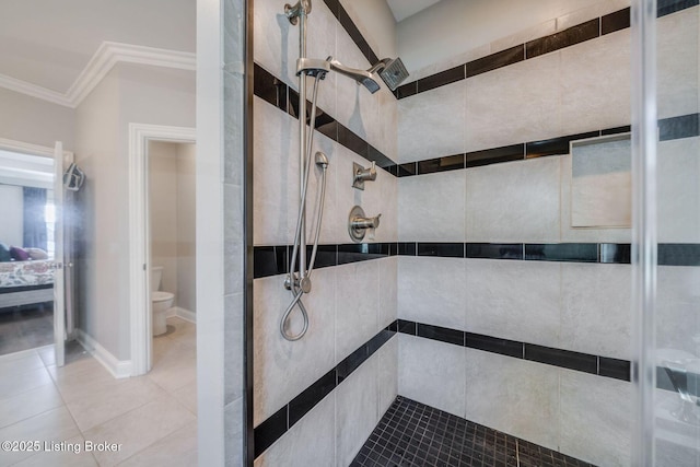 bathroom with tiled shower, toilet, crown molding, and tile patterned floors