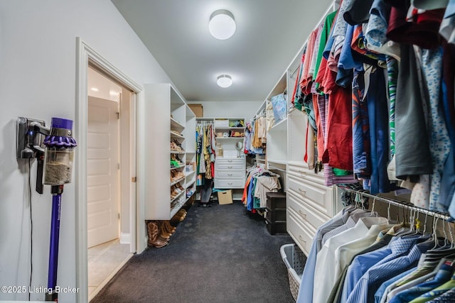 walk in closet featuring dark carpet