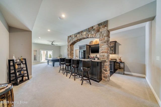 bar featuring ceiling fan, black refrigerator, and light carpet