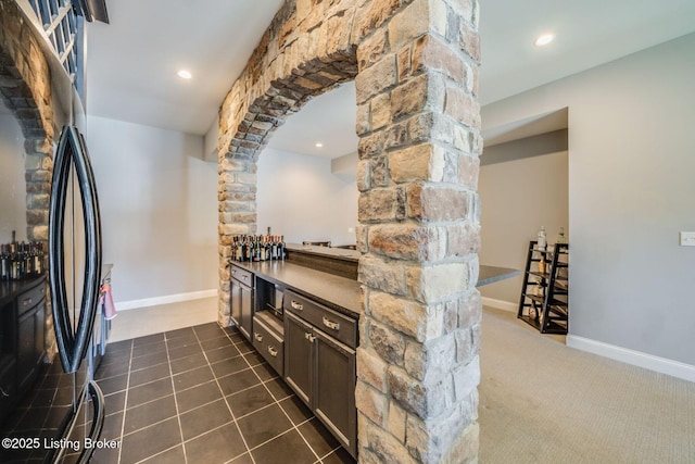 kitchen with decorative columns, black refrigerator, and dark tile patterned flooring