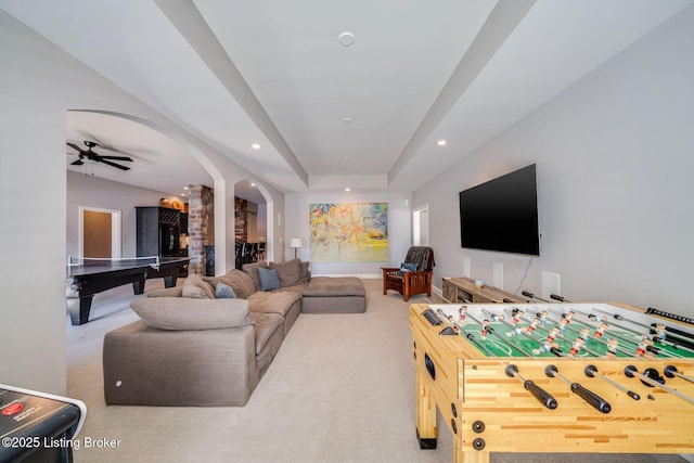 living room with ceiling fan, light carpet, and a tray ceiling