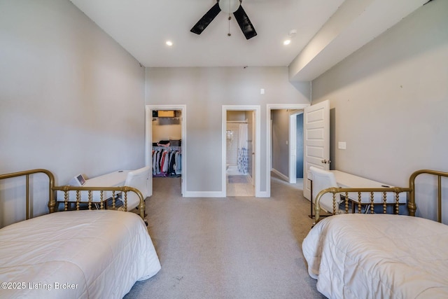 carpeted bedroom featuring ensuite bathroom, a closet, ceiling fan, and a walk in closet