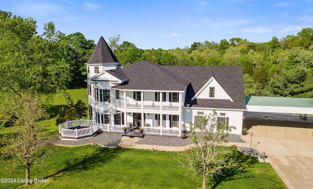 rear view of house with a lawn, a balcony, and a porch