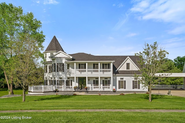 back of house featuring covered porch, a balcony, and a yard