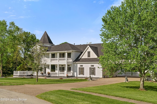 view of front facade featuring a balcony, a front lawn, and covered porch