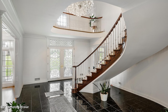 foyer with a wealth of natural light, a towering ceiling, french doors, and ornamental molding