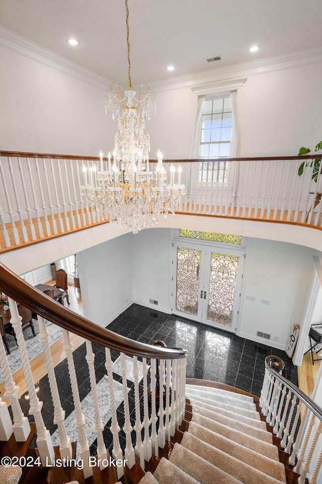 staircase with a notable chandelier, crown molding, and french doors