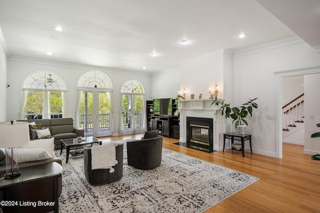 living room featuring light wood-type flooring, a high end fireplace, ornamental molding, and french doors