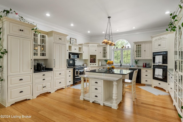 kitchen with a breakfast bar area, tasteful backsplash, decorative light fixtures, a kitchen island, and black appliances