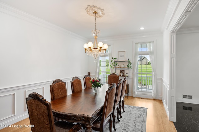 dining space featuring crown molding, light hardwood / wood-style floors, and a notable chandelier