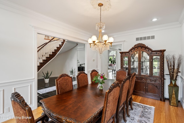 dining room with light hardwood / wood-style floors, crown molding, and a chandelier