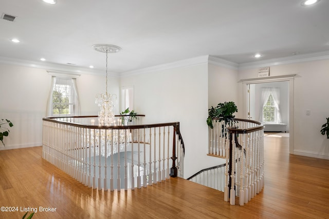 hall with light hardwood / wood-style floors, a chandelier, and ornamental molding