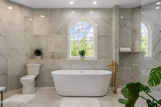 bathroom featuring tile walls, a bathtub, and toilet