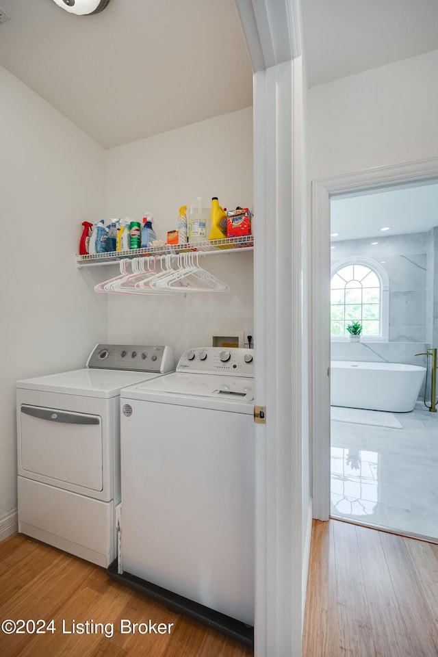 clothes washing area with hardwood / wood-style flooring and washing machine and clothes dryer