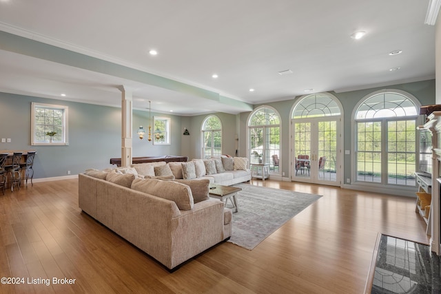 living room with light wood-type flooring, french doors, crown molding, and decorative columns