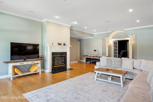 living room with light wood-type flooring, ornamental molding, and a fireplace