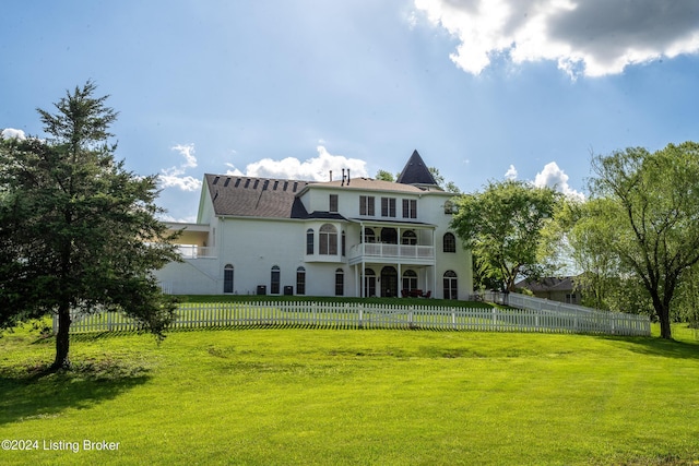 back of property with a lawn and a balcony