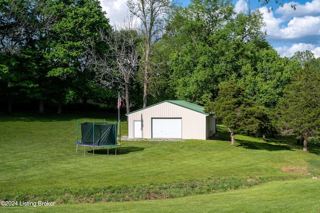 view of outbuilding with a garage, a yard, and a trampoline