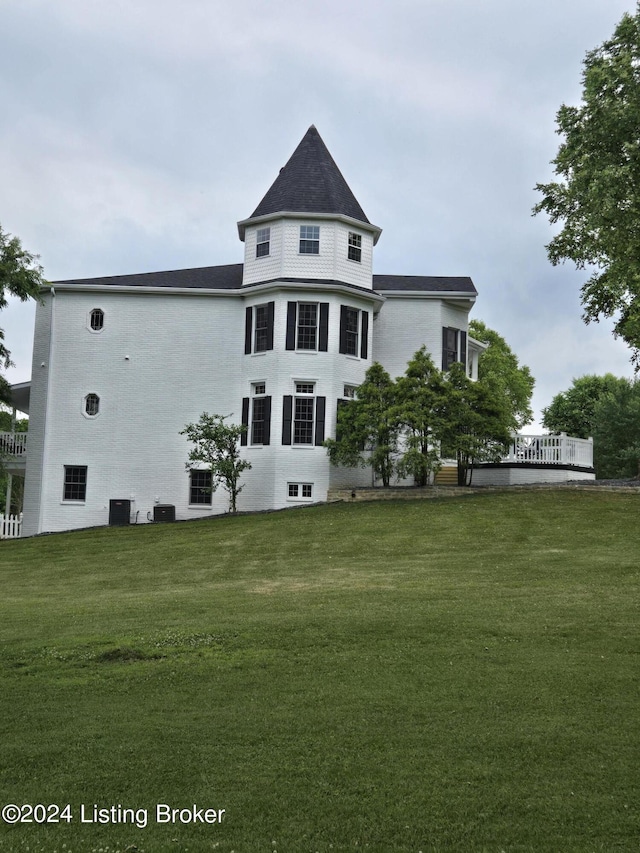 rear view of property featuring cooling unit and a yard