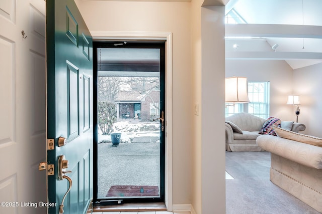 carpeted foyer featuring vaulted ceiling