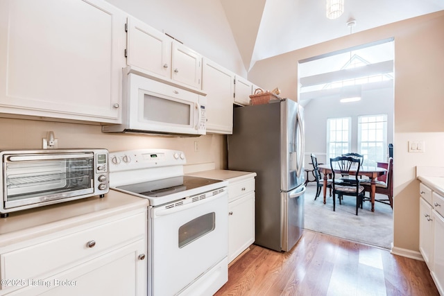 kitchen featuring white cabinets, decorative light fixtures, white appliances, and lofted ceiling