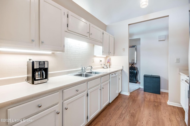 kitchen with sink, dishwasher, white cabinetry, and light hardwood / wood-style flooring