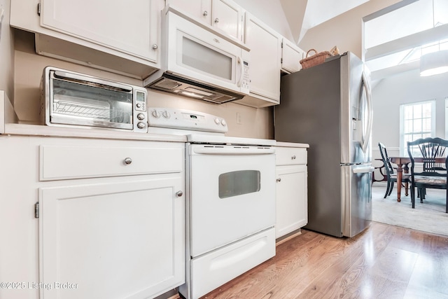 kitchen with vaulted ceiling, white appliances, light hardwood / wood-style flooring, and white cabinets