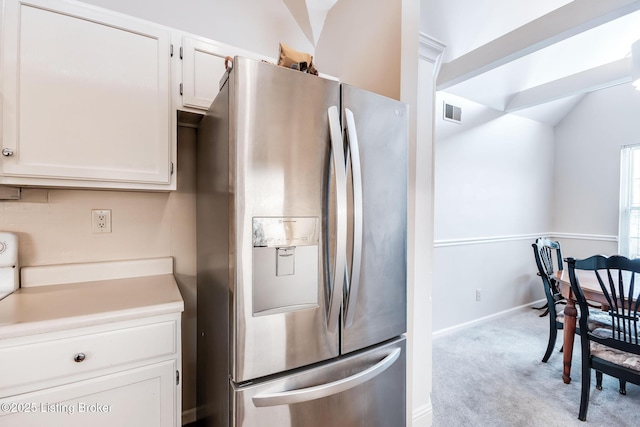 kitchen featuring light colored carpet, white cabinetry, stainless steel fridge with ice dispenser, and vaulted ceiling