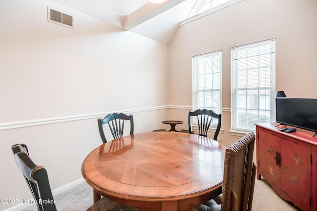 dining room featuring light carpet and vaulted ceiling