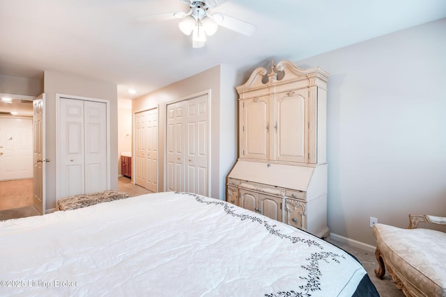 bedroom with ceiling fan, light colored carpet, and two closets