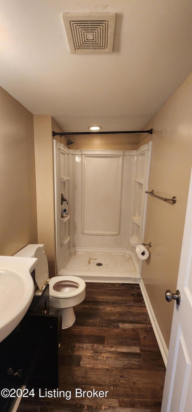 bathroom featuring toilet, a shower, sink, and hardwood / wood-style flooring