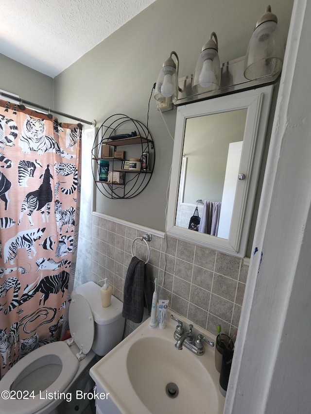 bathroom with a textured ceiling, sink, tile walls, toilet, and a shower with shower curtain