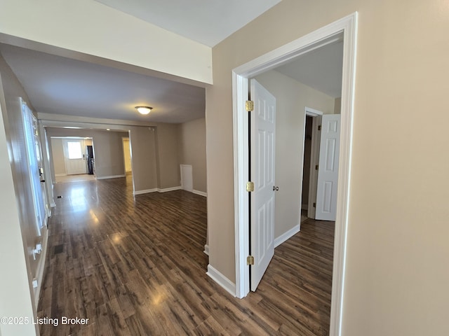 corridor with dark wood finished floors and baseboards