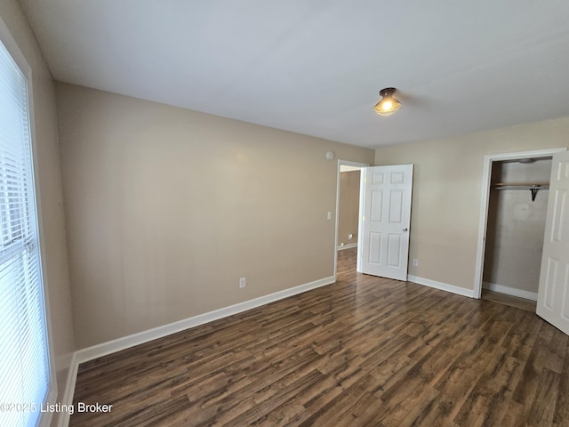 unfurnished bedroom with dark wood-style flooring, a closet, and baseboards