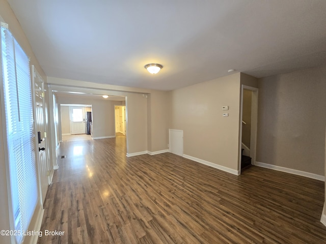 empty room with stairs, baseboards, and wood finished floors